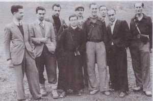 La fotografia è sulla copertina del libro intitolato: “L’eccidio di Braccano ed altri fatti della Resistenza nel territorio di Matelica e di Esanatoia”. Nella fotografia è rappresentato Don Enrico Pogognoni. I personaggi alla sua destra (a sinistra di chi guarda la fotografia) sono i capi della Resistenza di Matelica. Il terzo personaggio alla sinistra di Don Enrico è Tommaso Mari, uno dei cpai della Resistenza di Cerreto, che aveva contatti con Don Enrico e che non viene riconosciuto dagli autori del libro. Il quarto personaggio è Dalmato Seneghini, uno dei capi della Resistenza militare del San Vicino, segretario del Comitato di Liberazione Nazionale di Cerreto, in contatto con il Comandante Agostino della Sezione Porcarella della Brigata Garibaldi. In questa fotografia Seneghini non viene riconosciuto e non è nominato. La fotografia era di Giuseppe Baldini. Tommaso Mari, nominato nel libro come l’italo-americano era in realtà il collegamento con gli alleati, perchè sapeva l’inglese e per questo veniva utilizzato nella radio. Però non lo si identifica come capo della Democrazia Cristiana clandestina di Cerreto d’Esi e partecipante attivo alla Resistenza del versante nord del San Vicino. Giuseppe Baldini, che è nella fotografia con lui, sapeva certamente questa particolarità e probabilmente l’ha tenuta nascosta per ragioni di sicurezza. Ma nel libro si è persa, la memoria di questo collegamento. Non ci sono altre dimostrazioni di collegamenti fra queste storie e questa è la prova invece che il collegamento c’era e che è sconosciuto anche a chi è in possesso delle prove per dimostrarlo. 